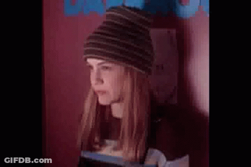Woman In Beanie And Striped Shirt Standing By Wall GIF