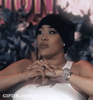 Woman In Beanie And White Tank Top Sitting With Hands Folded GIF