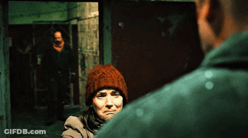 Woman In Beanie Looking At Man In Green Shirt GIF