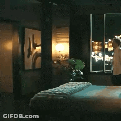 Woman In Bedroom Next To Bed And Window GIF