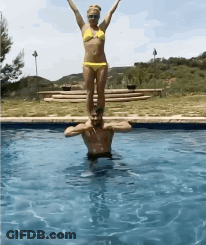 Woman In Bikini Standing On Man's Shoulders GIF