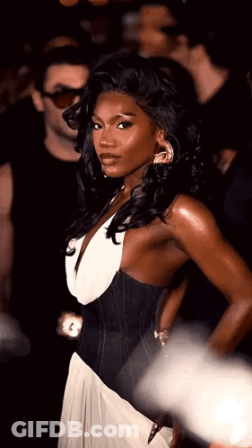 Woman In Black And White Dress Standing In Front Of Crowd GIF