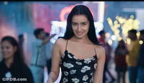 Woman In Black And White Floral Dress Smiling In Crowd GIF