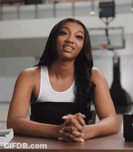 Woman In Black And White Tank Top Sitting At Desk With Hands Folded GIF