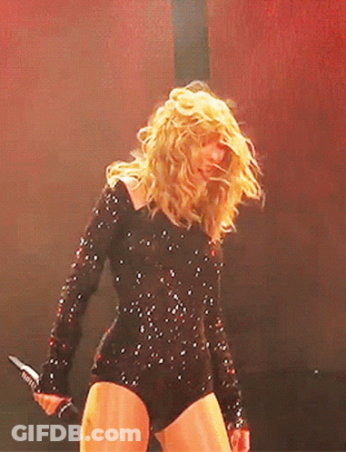 Woman In Black Bodysuit Holding Microphone On Stage GIF
