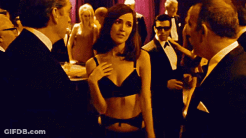 Woman In Black Bra Among Men In Tuxedos GIF