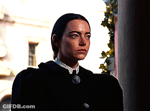 Woman In Black Coat And White Shirt With Medallion Necklace GIF