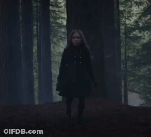 Woman In Black Coat Running Through Forest GIF