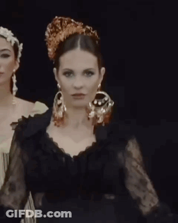 Woman In Black Dress And Earrings Next To Crowned Woman GIF