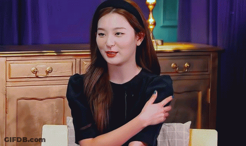 Woman In Black Dress And Headband Sitting At Table GIF