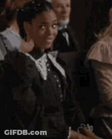 Woman In Black Dress And White Collar Smiling In Crowd GIF
