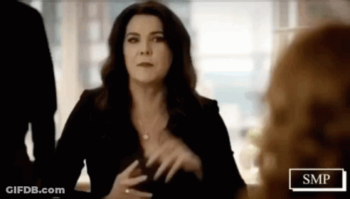 Woman In Black Dress At Table With SMP Sign GIF