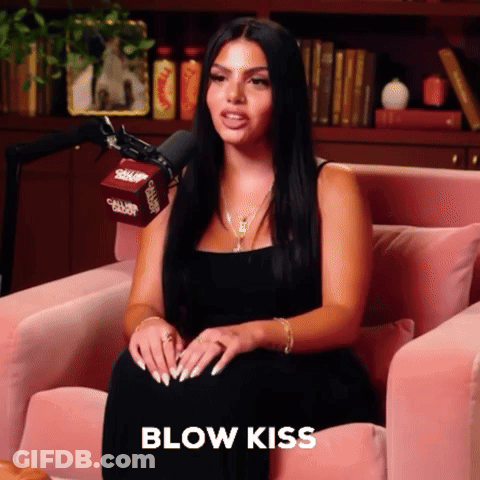 Woman In Black Dress Blowing Kiss In Pink Chair GIF