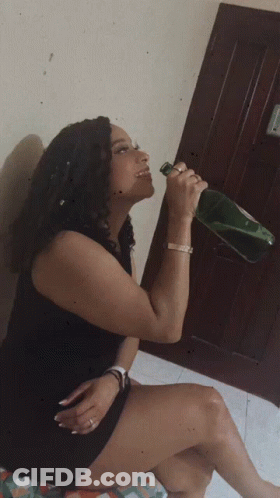 Woman In Black Dress Drinking From Green Bottle GIF