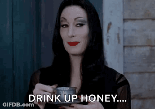 Woman In Black Dress Holding Coffee Saying Drink Up Honey GIF