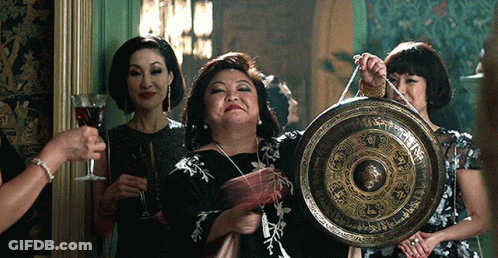 Woman In Black Dress Holding Gong With Chinese Writing GIF