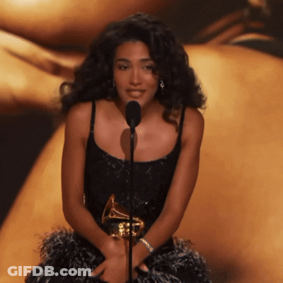 Woman In Black Dress Holding Grammy At Microphone GIF