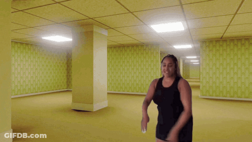 Woman In Black Dress In Empty Yellow Hallway GIF