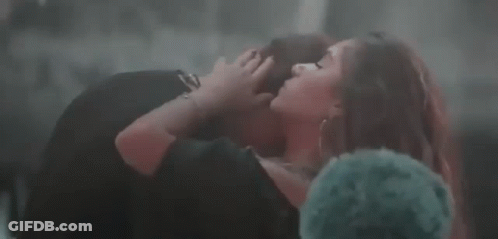 Woman In Black Dress Kissing Man On Lap GIF