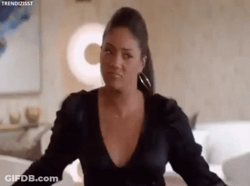 Woman In Black Dress Looking At Camera In Living Room GIF