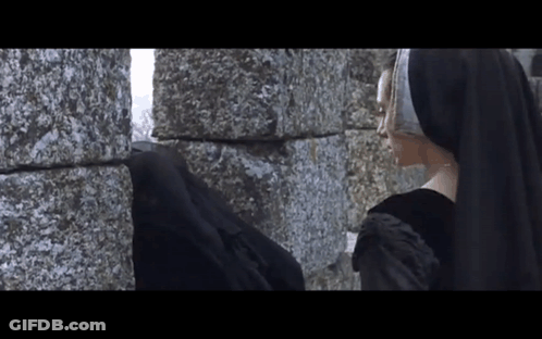 Woman In Black Dress Next To Stone Wall GIF