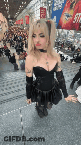Woman In Black Dress On Stairs In Front Of Crowd GIF