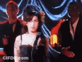 Woman In Black Dress Singing Into Microphone GIF