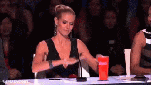 Woman In Black Dress Sitting At Table With Red Cup GIF