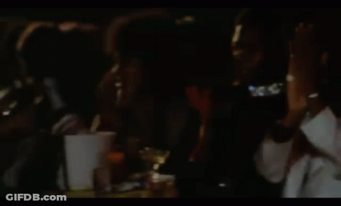 Woman In Black Dress Sitting Beside Man In Pink Jacket GIF