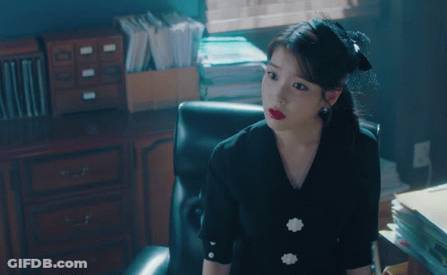 Woman In Black Dress Sitting In Chair In Office GIF