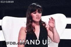Woman In Black Dress Sitting With Hands Up Saying Hand Up GIF