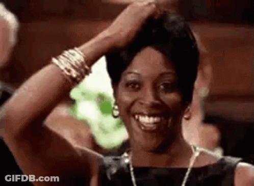Woman In Black Dress Smiling And Holding Hair GIF