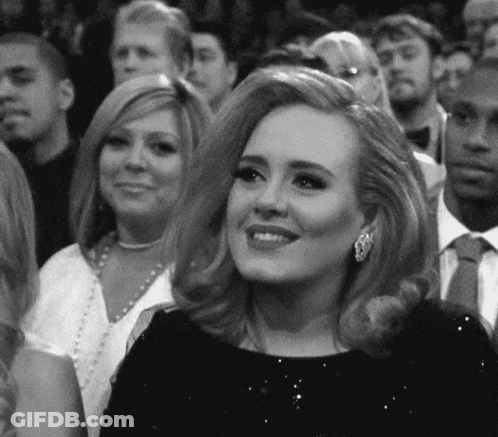 Woman In Black Dress Smiling In Crowd GIF
