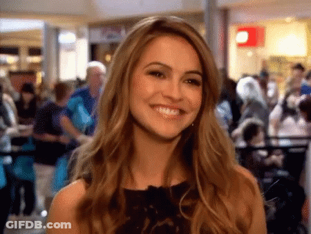 Woman In Black Dress Smiling In Crowded Mall GIF