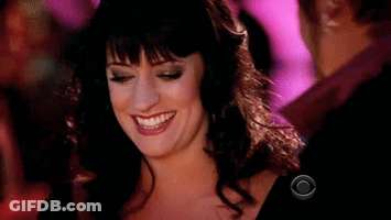 Woman In Black Dress Smiling In Front Of Man In Pink Shirt GIF