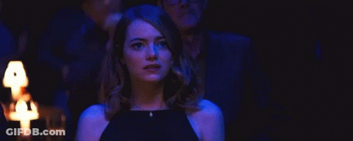 Woman In Black Dress Standing In Dark Room Before Group GIF