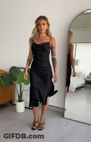 Woman In Black Dress Standing In Front Of Mirror GIF