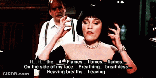 Woman In Black Dress Talking To Man In White Shirt And Suspenders GIF