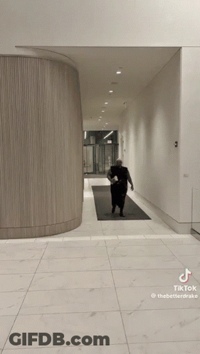 Woman In Black Dress Walking Down Hallway TikTok Watermark GIF