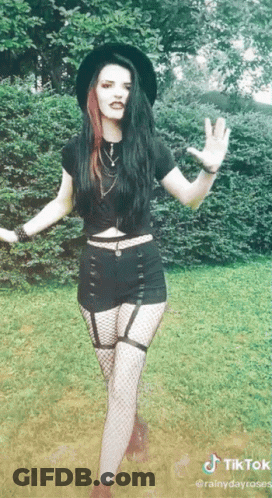 Woman In Black Hat And Fishnets In Grass GIF