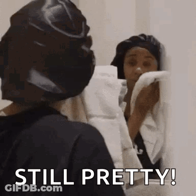 Woman In Black Hat Holding Towel Looking Mirror GIF