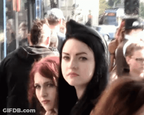Woman In Black Hood Stands In Crowd GIF
