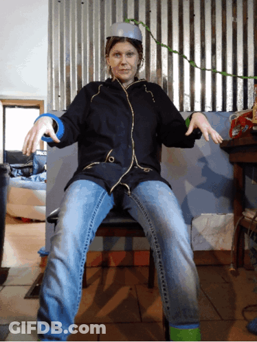 Woman In Black Jacket And Blue Jeans Sitting With Arms Outstretched GIF