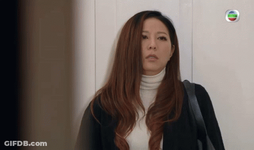 Woman In Black Jacket And White Turtleneck In Front Of TV Channel Logo GIF