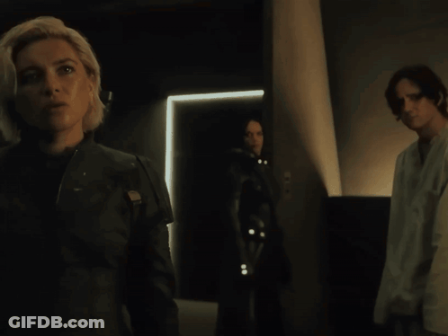Woman In Black Jacket In Dark Room With Two People GIF