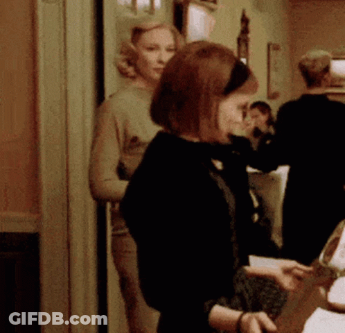 Woman In Black Jacket Standing In Hallway GIF