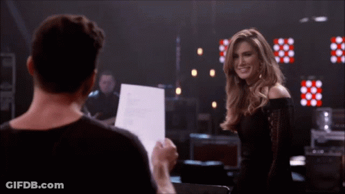 Woman In Black Lace Top Smiling In Red Chair GIF