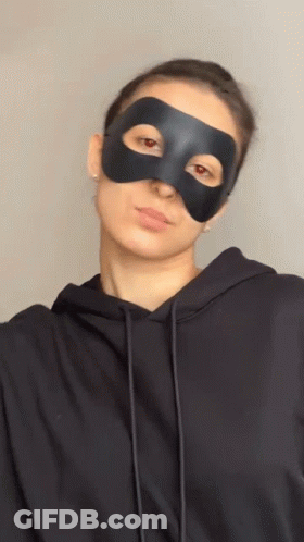 Woman In Black Mask And Hoodie Looking At Camera GIF