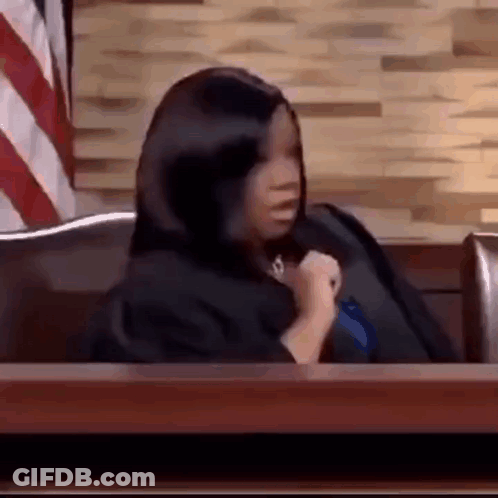 Woman In Black Robe Sitting At Courtroom Table GIF