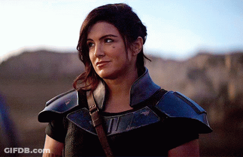 Woman In Black Shirt And Blue Armor Looking Sideways GIF